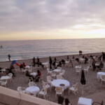 Udsigt over stranden fra Promenade des Anglais. Man kan se folk på stranden og en af strandrestauranterne