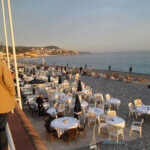 Udsigt over stranden fra Promenade des Anglais. Man kan se folk på stranden og en af strandrestauranterne